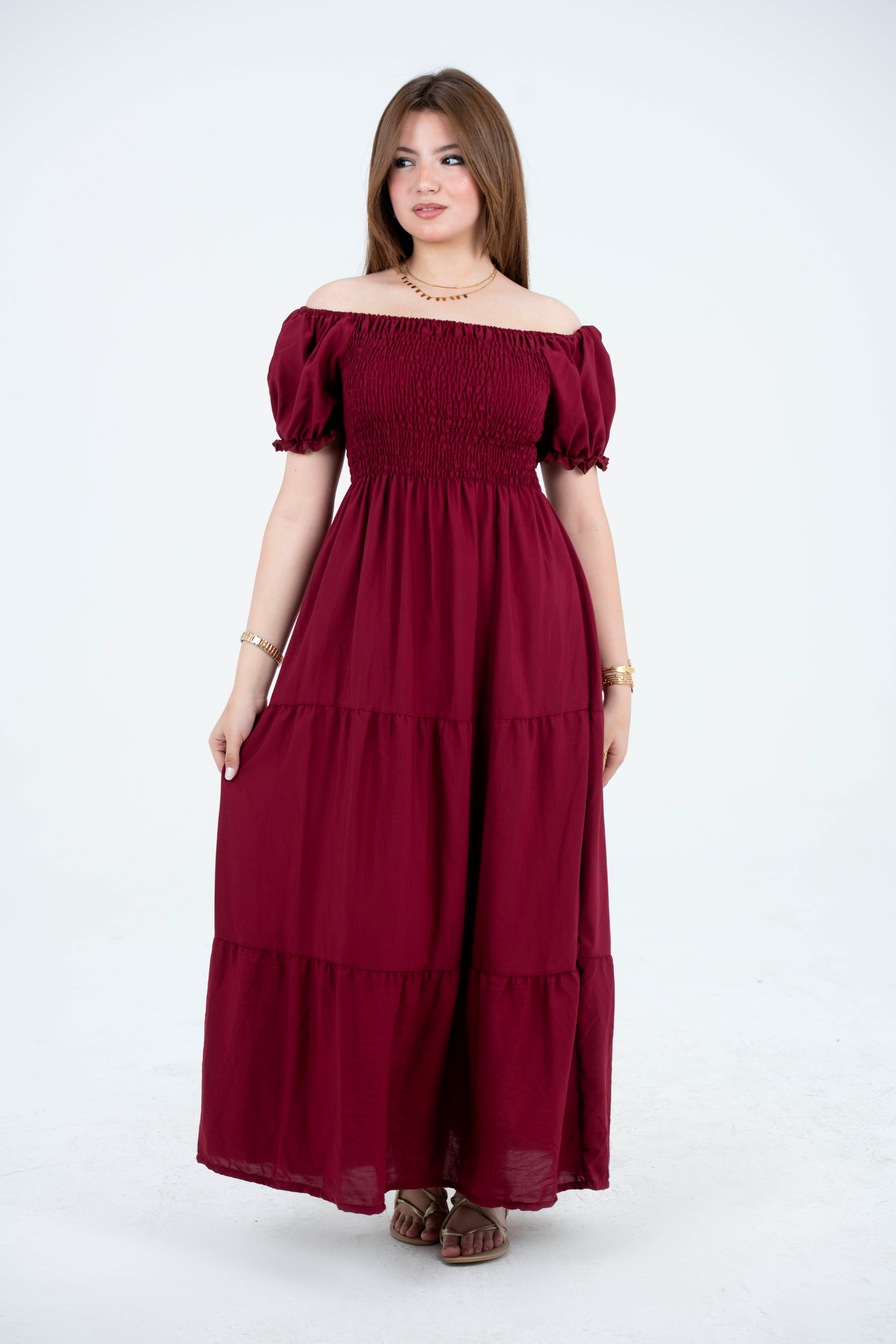 Woman wearing a burgundy off-shoulder dress on a white background