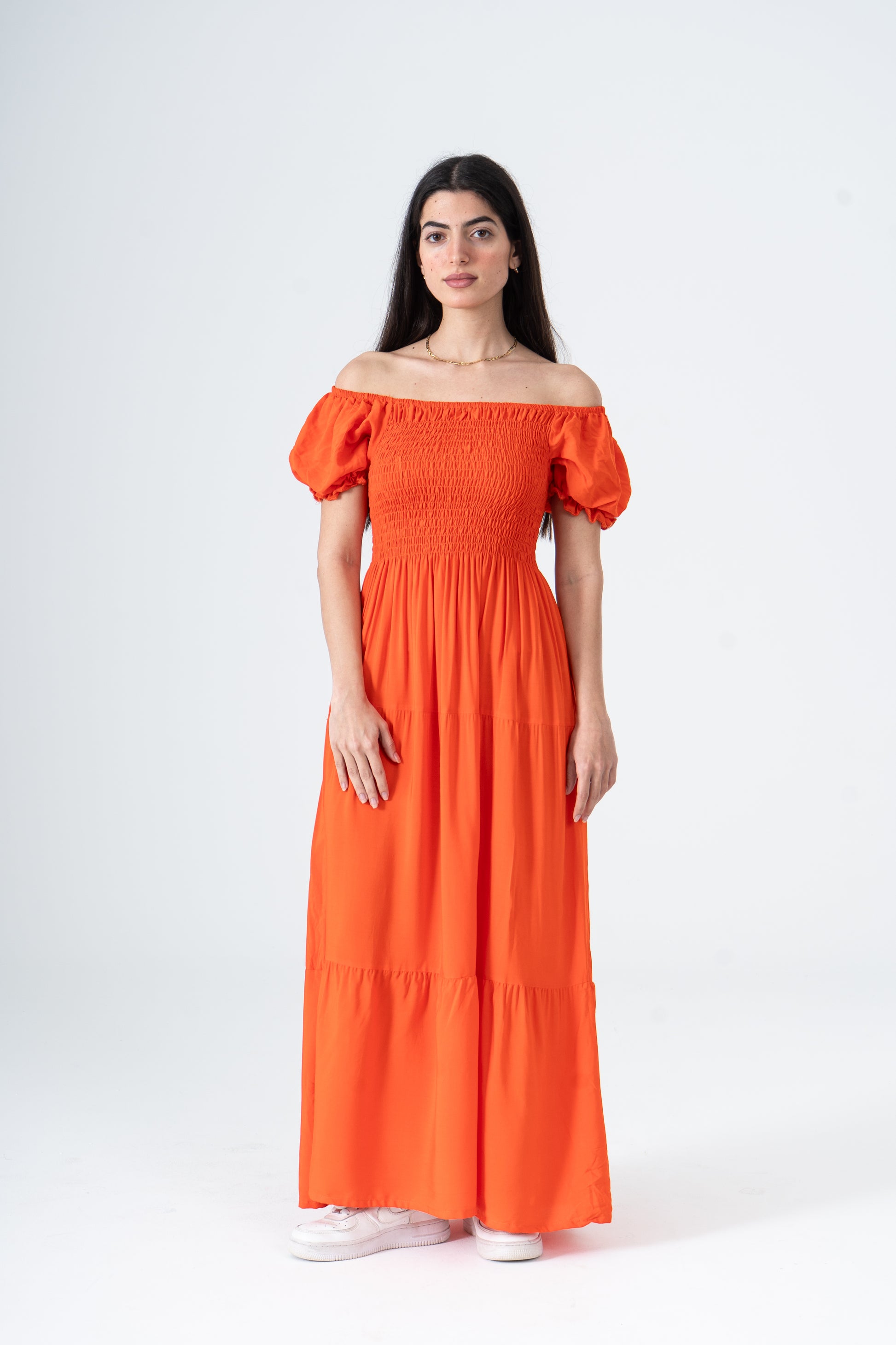 Woman wearing an orange off-shoulder dress on a white background